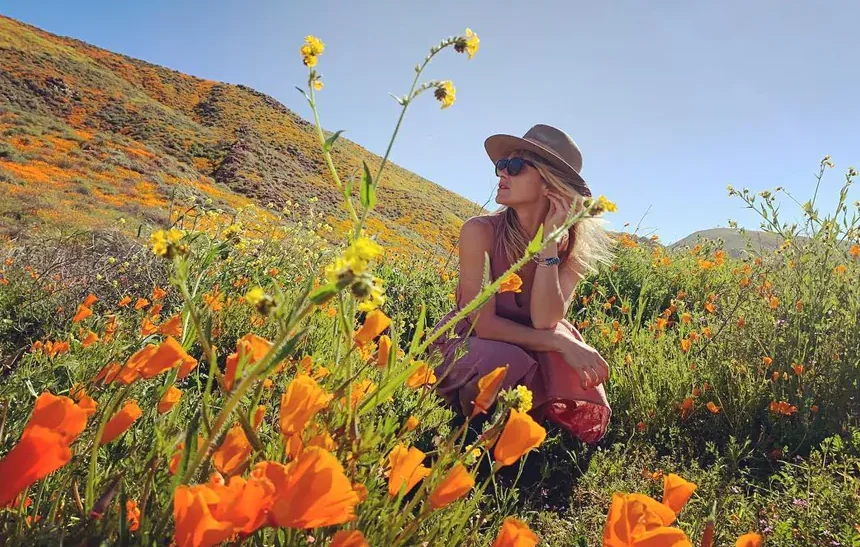 Beau Garrett sitting in a wildflower field, reflecting her estimated $11 million net worth lifestyle in 2026