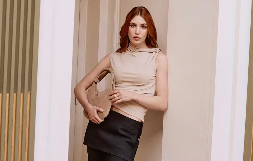 Sophie Nelisse in a beige turtleneck top holding a suede handbag, representing her $5 million net worth in 2026