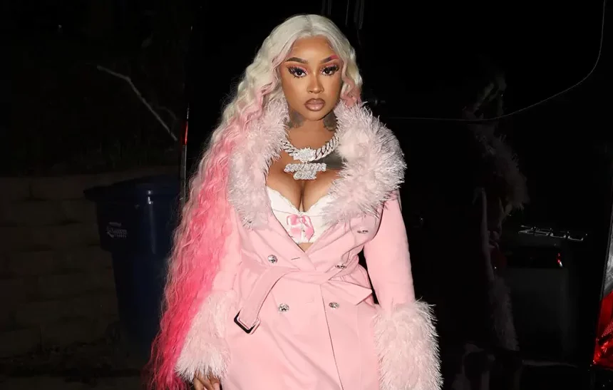 Stunna Girl net worth — rapper wearing pink fur coat and diamond chain necklace at a night event
